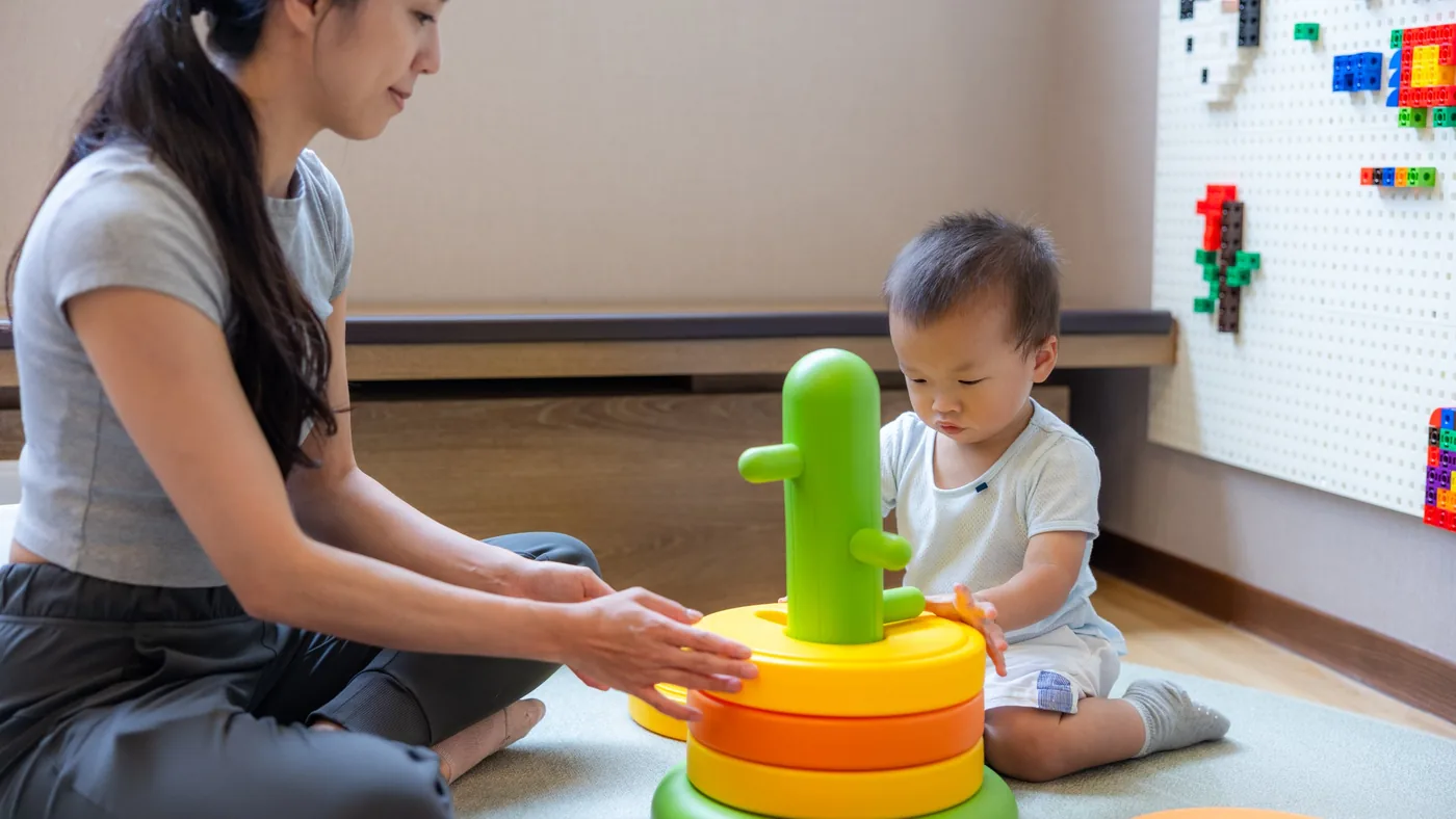 Una adulta y un niño pequeño jugando juntos en el suelo